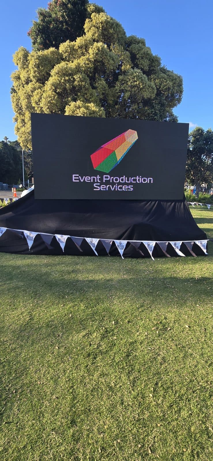 Large screen displaying the Event Production Services logo at a Bay of Plenty event